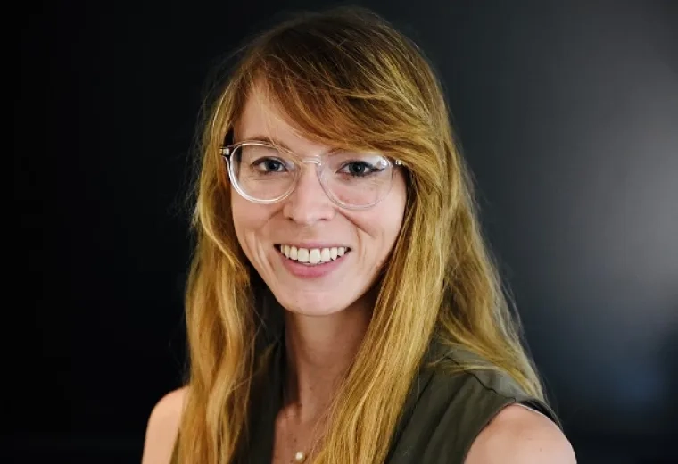 emma wears clear rimmed glasses and has strawberry blonde hair