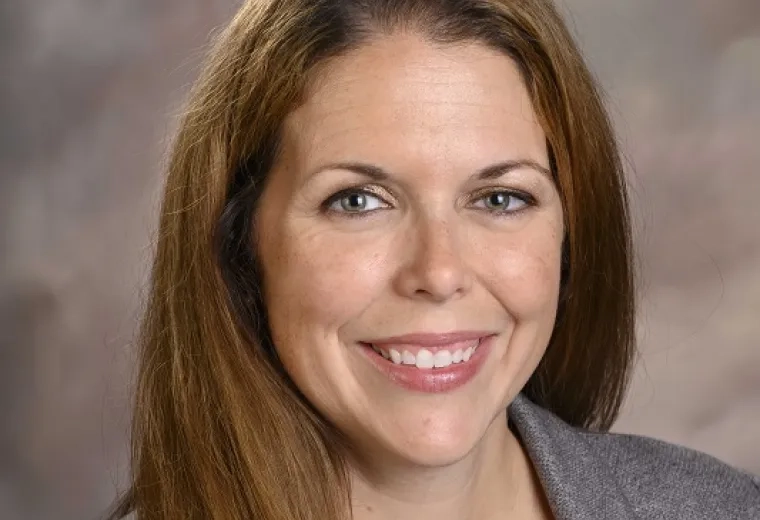 haley wears a grey blazer and has long reddish brown hair