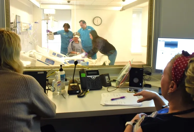 Nursing faculty watching  students work with a simulated participant in the IHP's Simulation Lab.