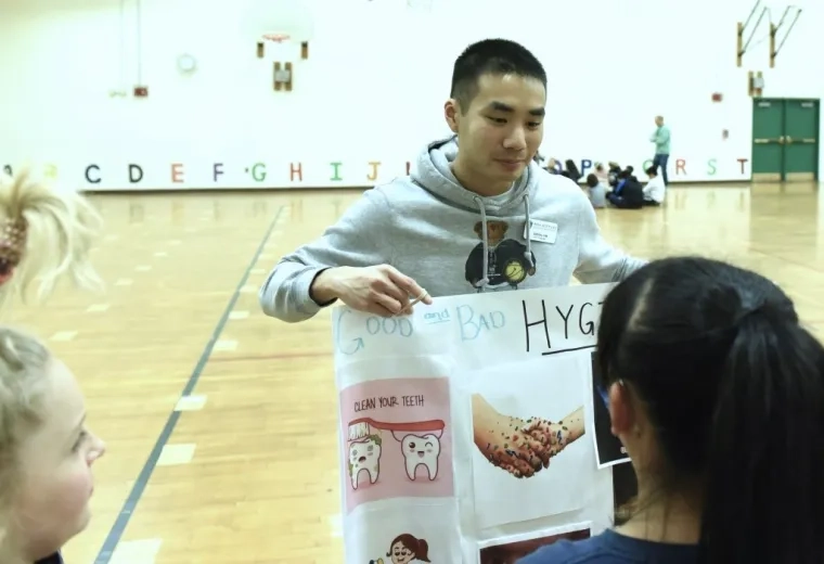 Man pointing out things in a poster to school children