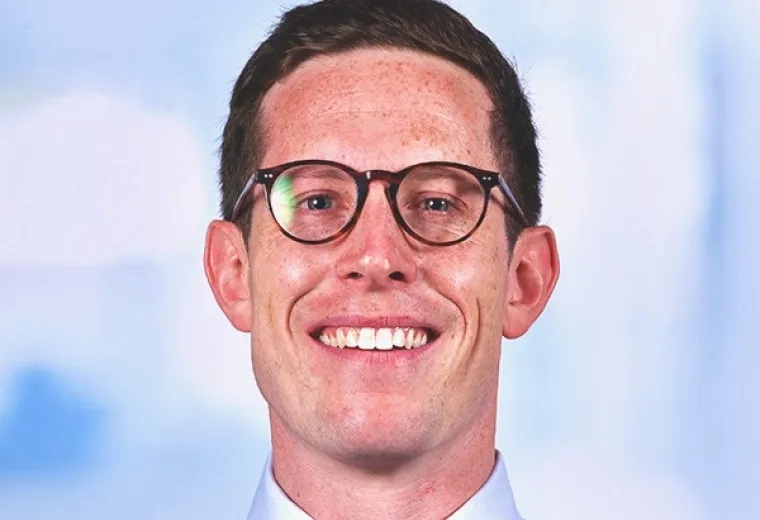 Alex Wolf wearing glasses and in light blue shirt and green bowtie