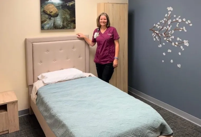 woman stands next to bed