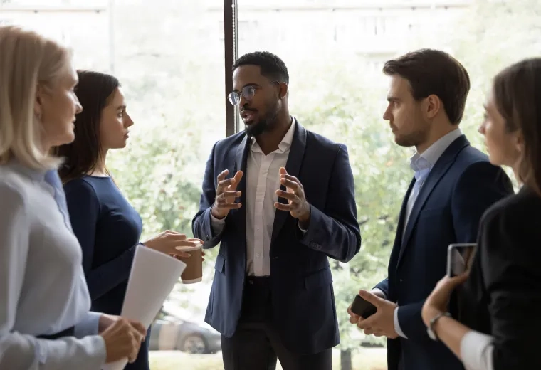 man in suit speaking to group of other professionally dressed people