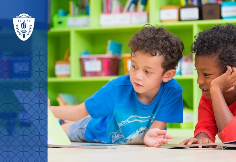 two young boys read a book on the floor in front of a colorful wall of books