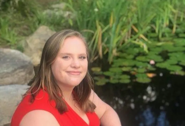 Lauren Talbourdet in red, short sleeved shirt and blue jeans. Lauren has shoulder-length, straight blonde hair.