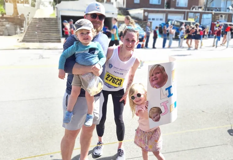 women in tank top with race bib attached smiles with man and two children in the street