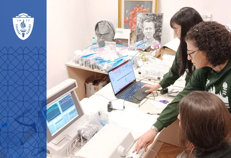 three people work at computers with various technology on the table