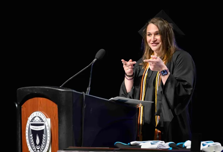 Woman in cap and gown talking at podium