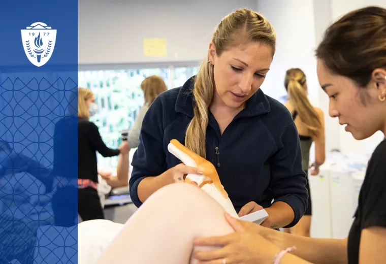 Two physical therapy students practicing hands-on techniques during a lab session, with a focus on joint manipulation.