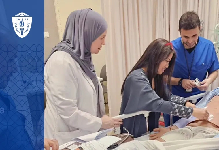 a woman shows two students something on a manikin's stomach at a hospital bedside