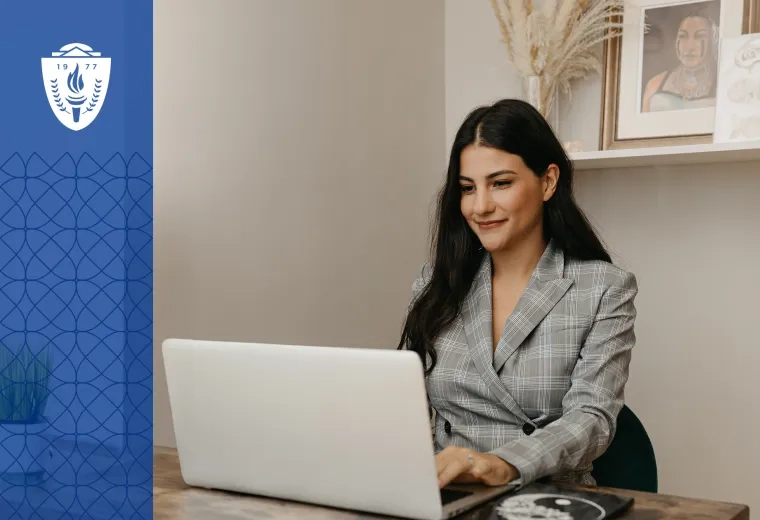 woman in plaid jacket sits at laptop in a cream colored room
