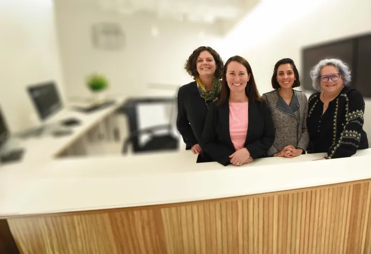 four women stand behind a desk