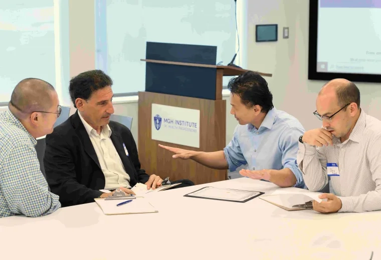 Four men talking around a table
