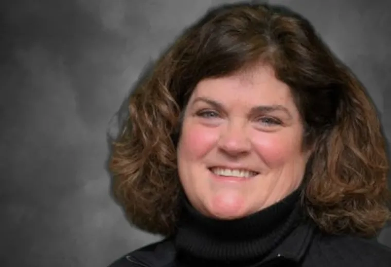 Deanna Denault has shoulder-length brown hair and is wearing a black turtle neck