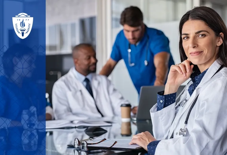 woman in lab coat sits at a conference table and knowingly smiles at the camera