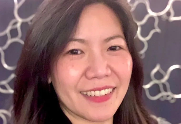 Jenny Ling Hui Loh has long dark brown hair and is wearing a black blazer and pink shirt