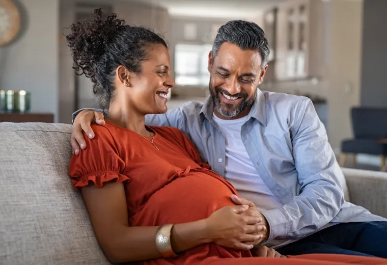 smiling man and pregnant woman on a couch