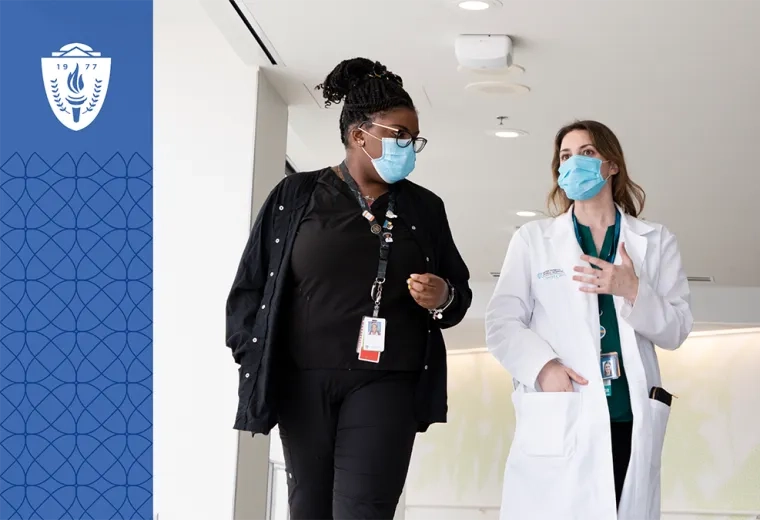  woman in white lab coat walking with another woman in the hospital