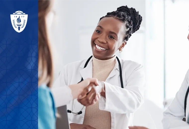 woman in white coat and stethoscope shakes the hand of another person off camera