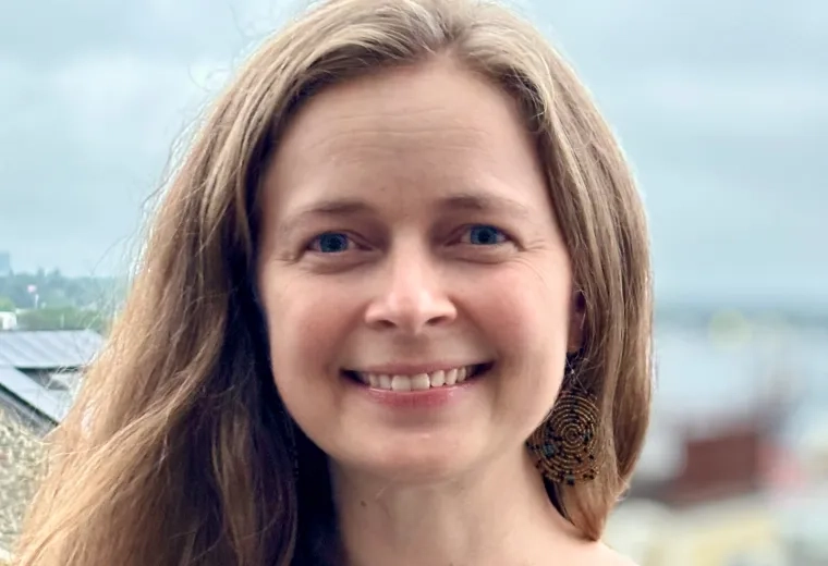 Maria Openshaw has medium length light brown hair is is wearing a grey t-shirt