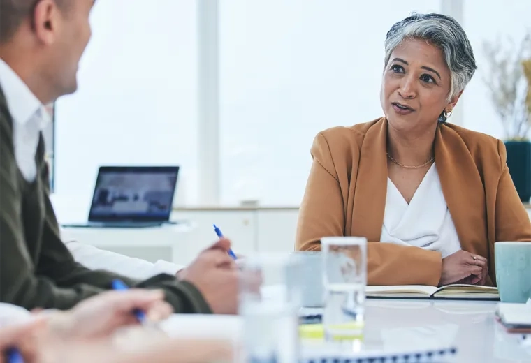 woman with short grey hair sits at a conference table
