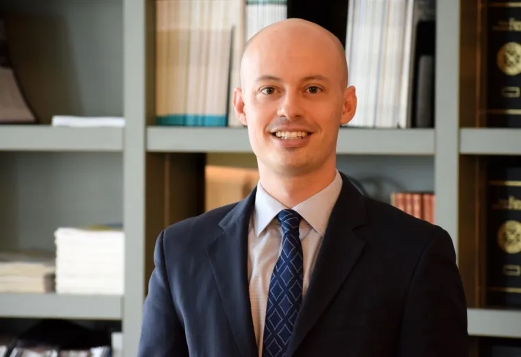 brendan stands in front of a bookshelf