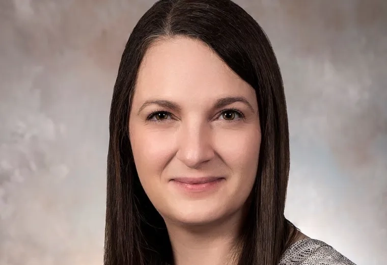 Erin Barry has long brown hair and is wearing a patterned white shirt