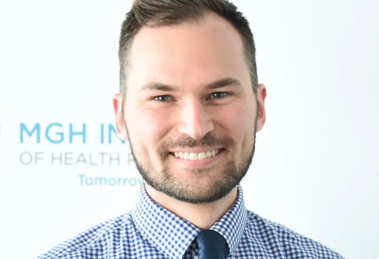 ben has a close cropped beard and mustache and wears a blue checkered shirt with a navy tie