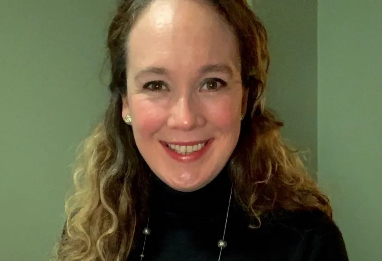 Meaghan Costello has curly, long hair and is wearing a black turtleneck