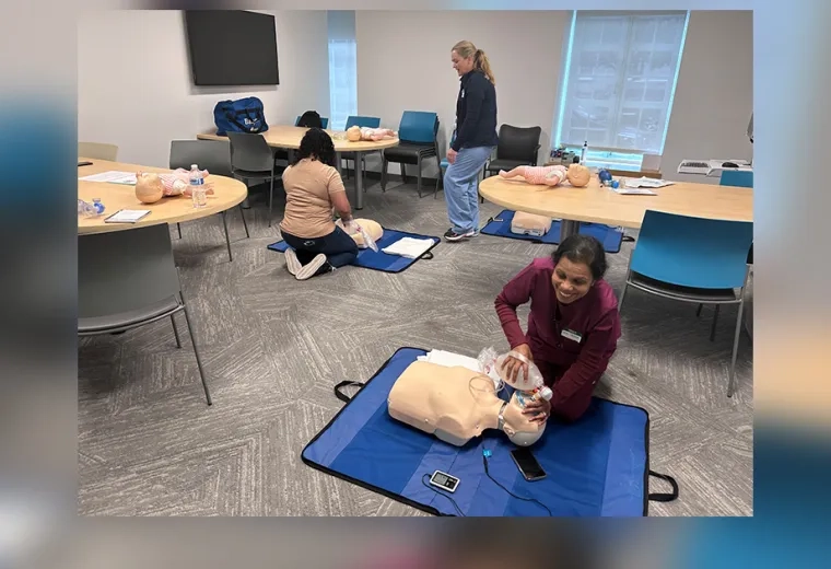 woman kneels in front of a manikin torso on the floor