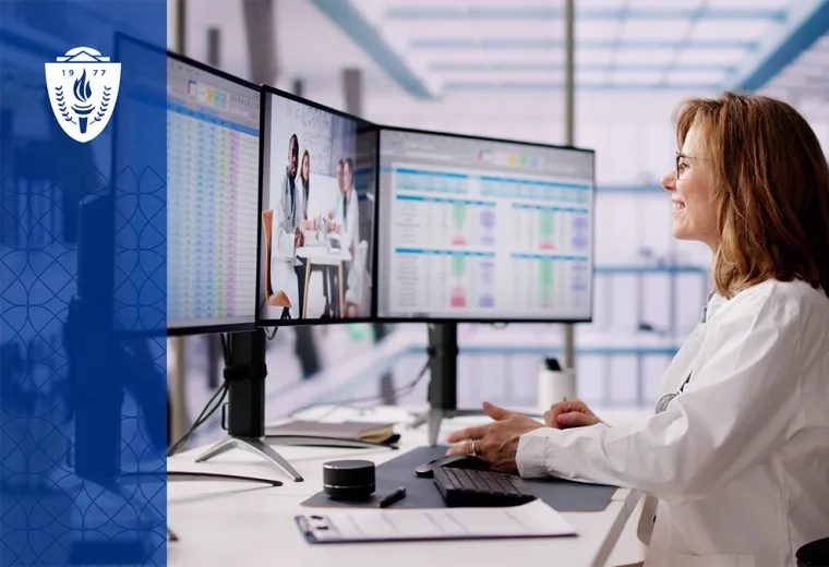 a woman in a white lab coat looks at data on three computer screens