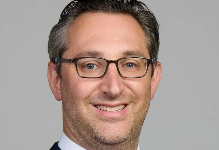 jared has glasses and a red tie with a navy jacket