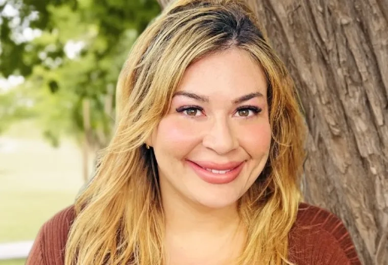 Rachel Terra Norton has medium length blonde hair and is wearing a brown shirt.