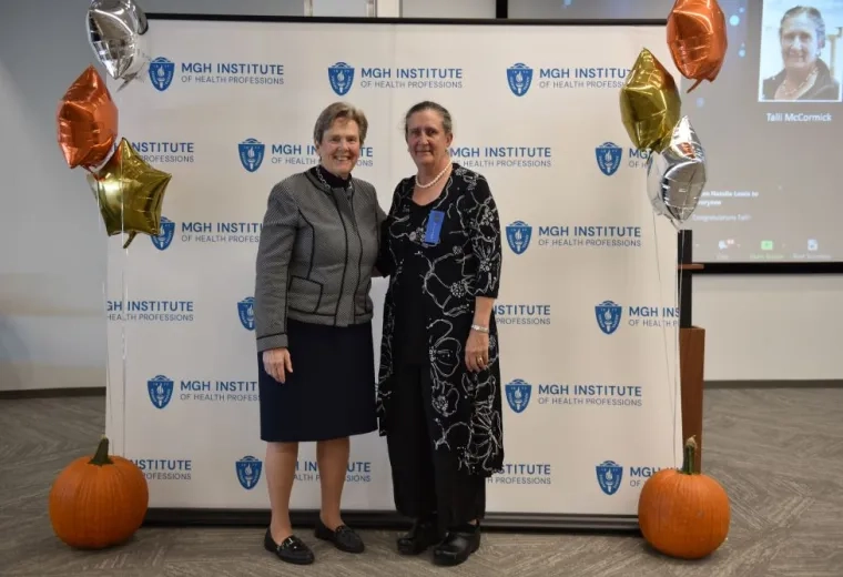 two women stand in front of MGH banner