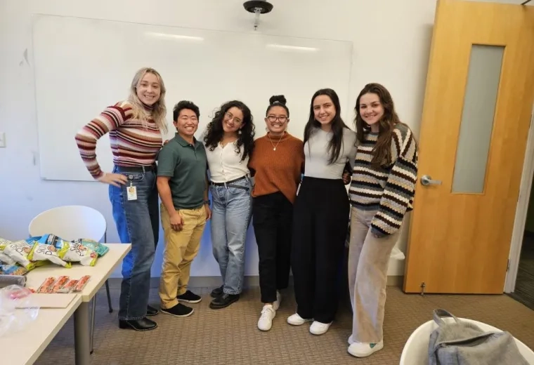Six women pose standing next to each other