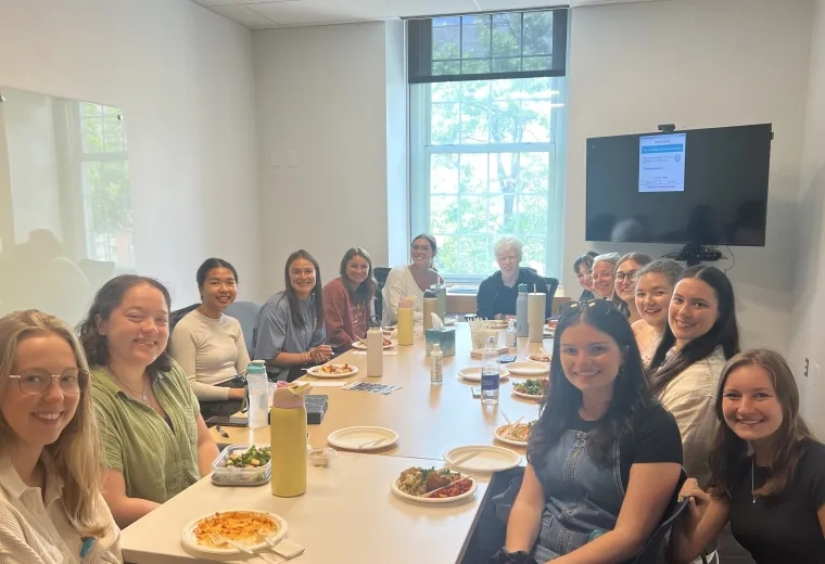 People sit at a table with food in front of them posing for the camera