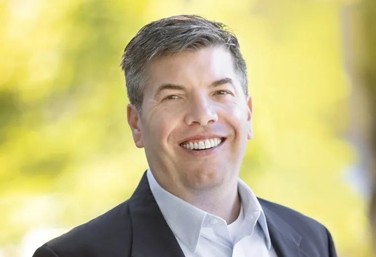 steve wears a dark suit jacket and white collared shirt in front of a bright background