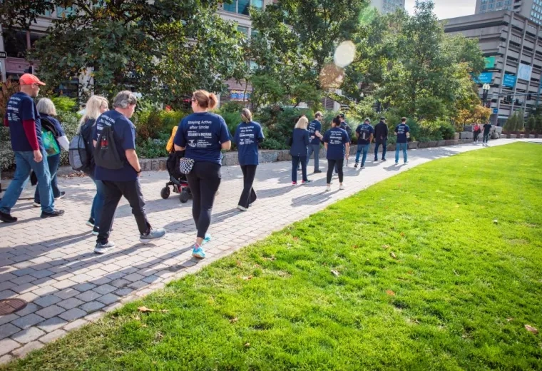 People wearing blue shirts walk along a walkway