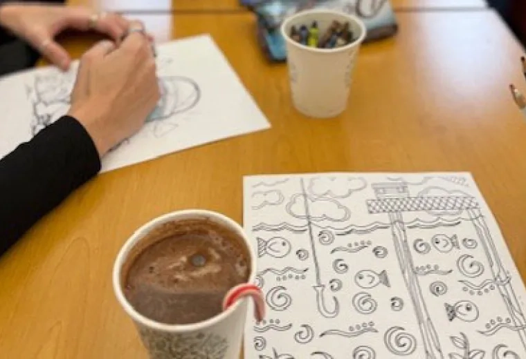 hand with hot cocoa and coloring page