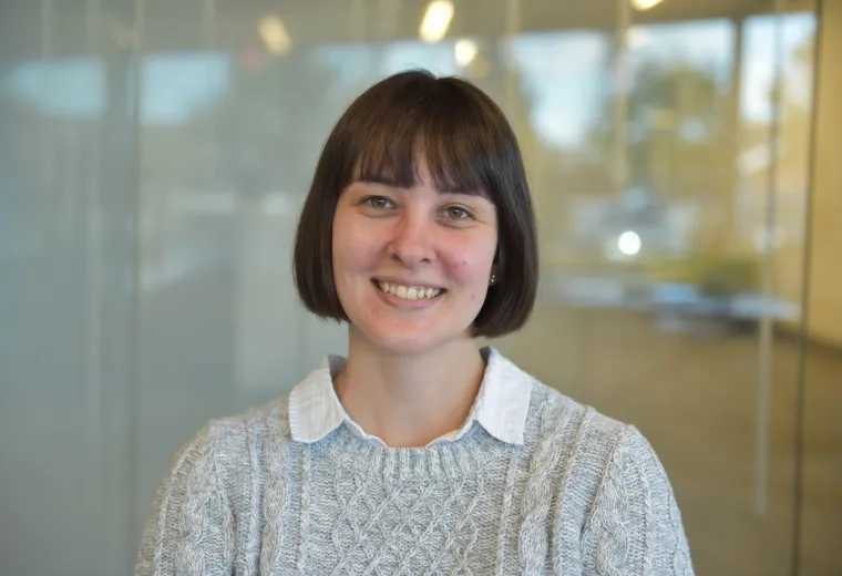 tyler wears a grey sweater with a white collar shirt underneath