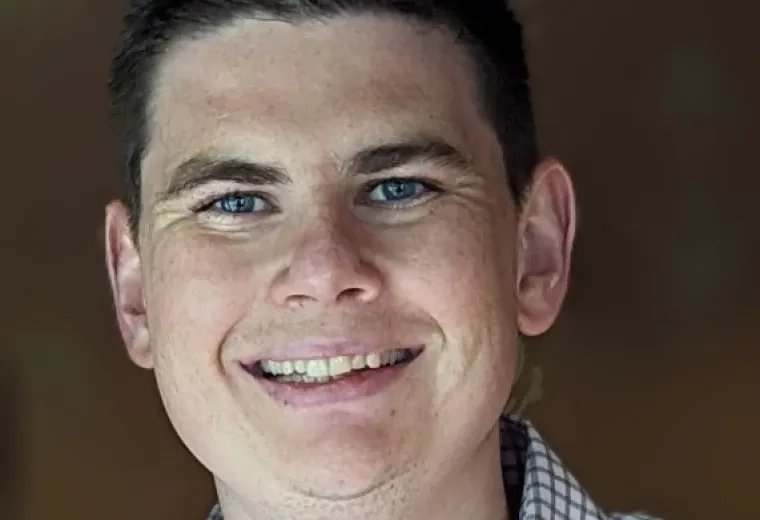 Matt O'Sullivan has short brown hair and is wearing a white and black plaid shirt