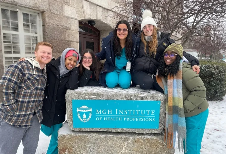 students in scrubs gather around the IHP sign on campus