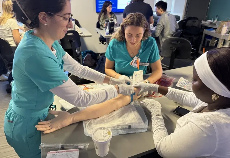 3 women giving IV to fake arm