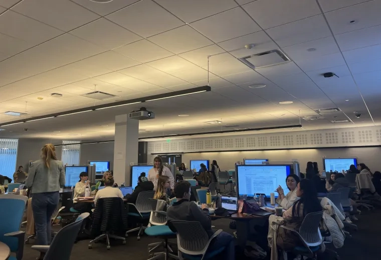 A room with tables that have large monitors with people sitting 