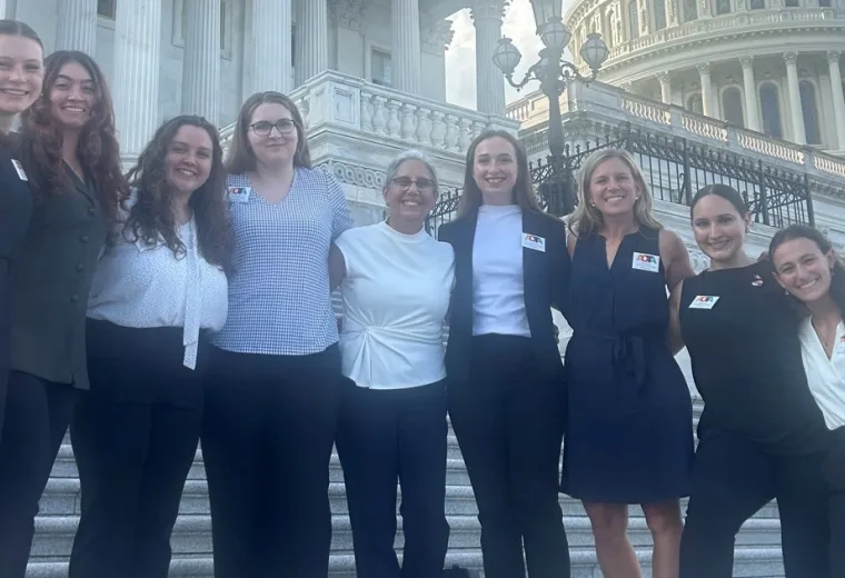 Nine people stand on steps with the US Capitol in the background