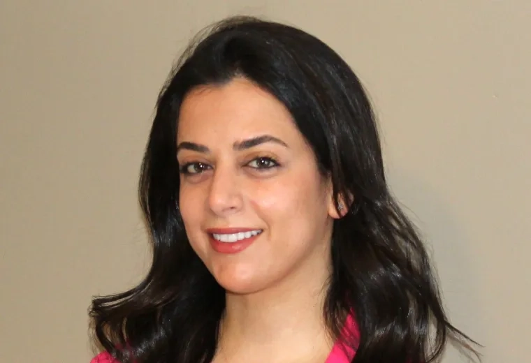 Ingrid Korbani has long black hair and is wearing a white shirt and hot pink blazer