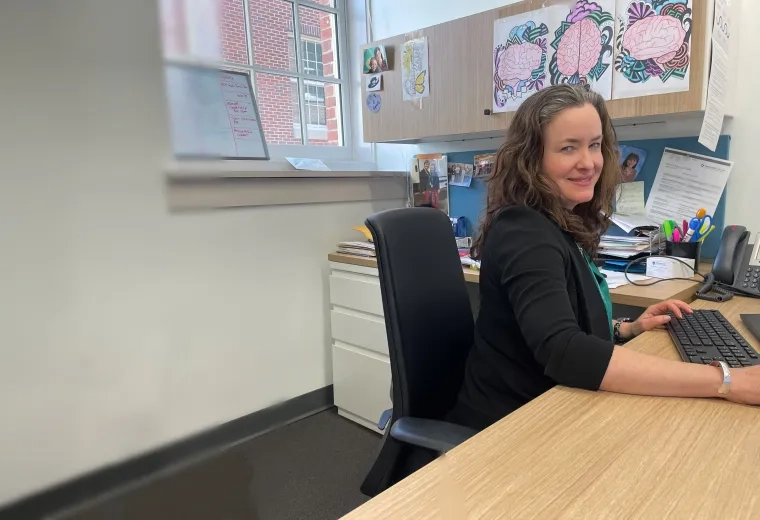 A woman sits at a desk with a keyboard in front of her
