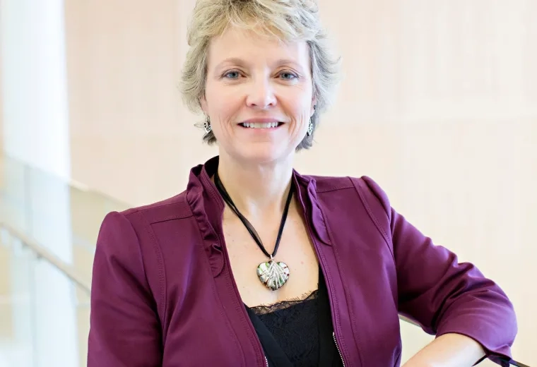 Lisa Donegan Shoaf has short light blond hair and is wearing a black shirt and dark purple jacket