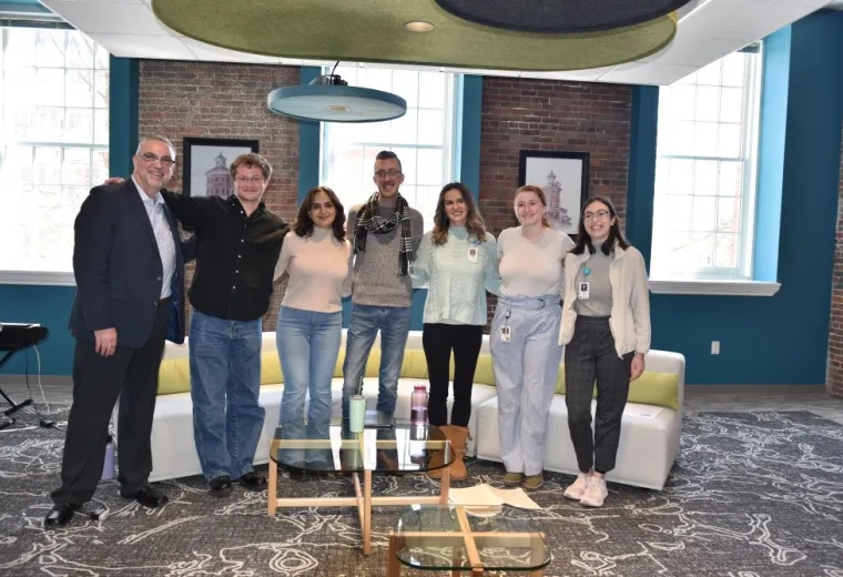 Seven people pose together in front of a couch