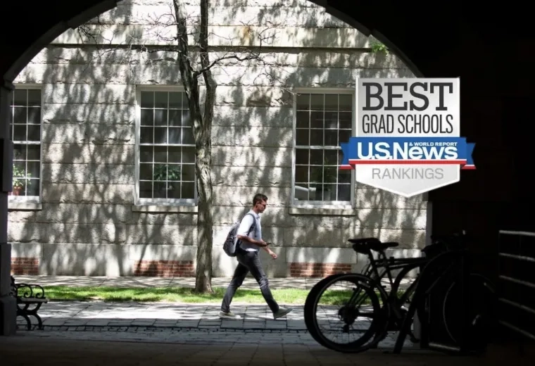 Photo of a person walking in front of a building with a bike on the right framed by the entrance to another building
